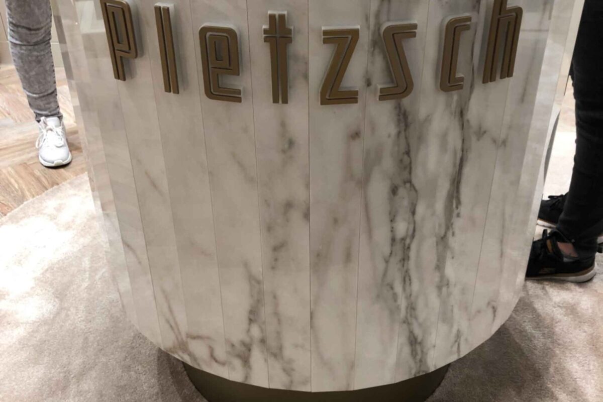 Einzelbuchstaben aus Acrylglas in Gold lackiert schöne Gestaltung ainer Marmor Präsentationssäule bei einen Juwelier in FRankfurt am Main