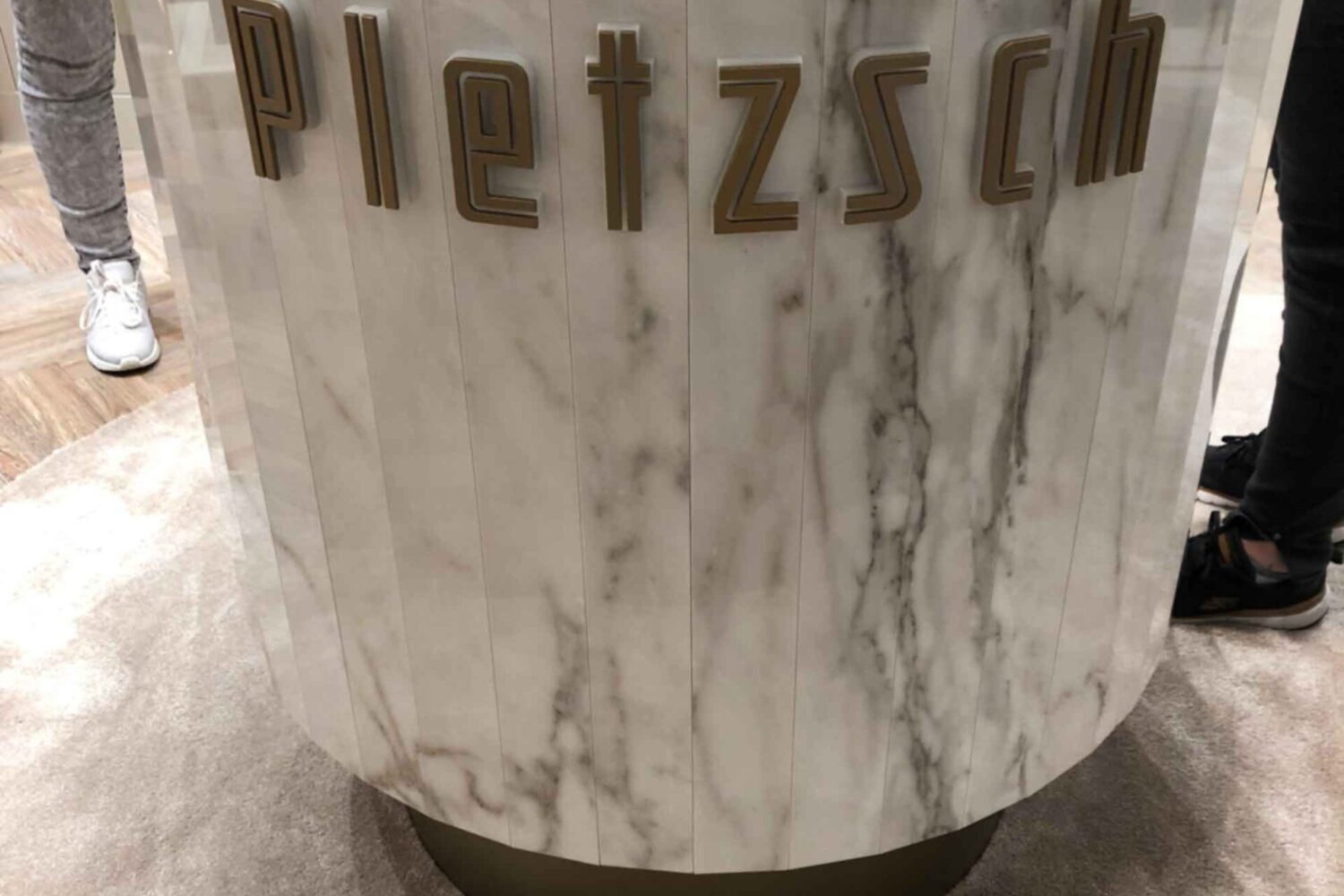 Einzelbuchstaben-auf-Abstand3 Einzelbuchstaben aus Acrylglas in Gold lackiert schöne Gestaltung ainer Marmor Präsentationssäule bei einen Juwelier in FRankfurt am Main