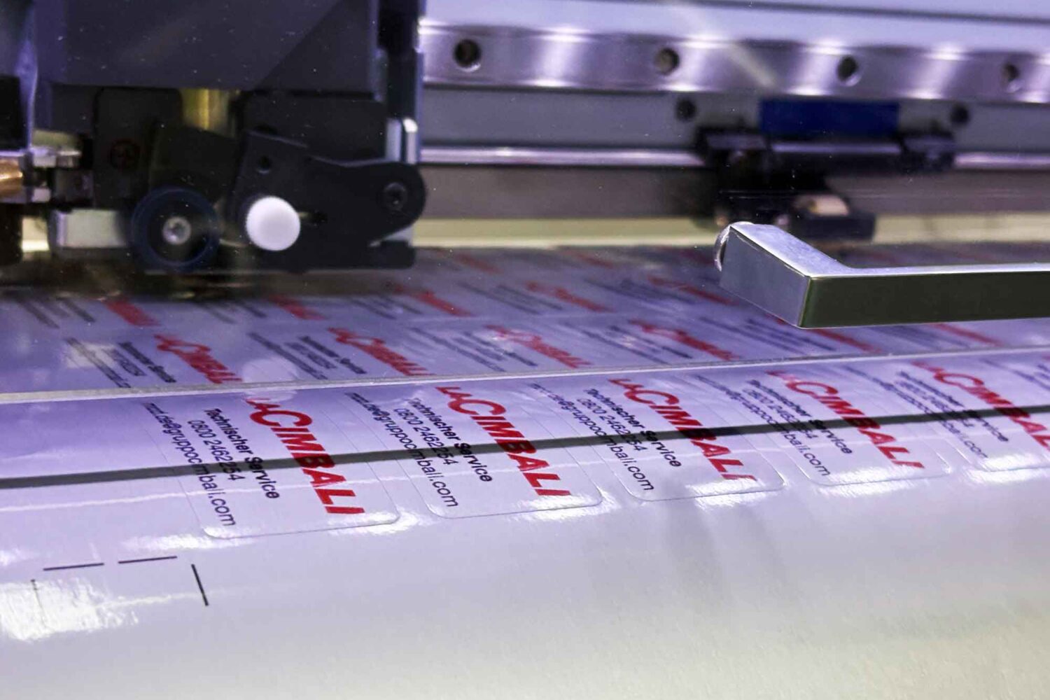Aufkleber-Zuschnitt-mit-Roland-VG2-Auhleber-Großserien-Produktion Druckmaschine Roland VG2 640 beim Drucken von Etiketten Silbern für Cimbali Kaffeemaschienen mit Zuschnitt auf Freiform